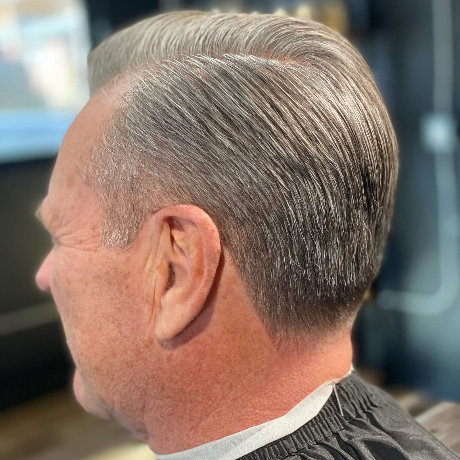 Tapered gray pompadour with clean sides cut at S|X Barbershop