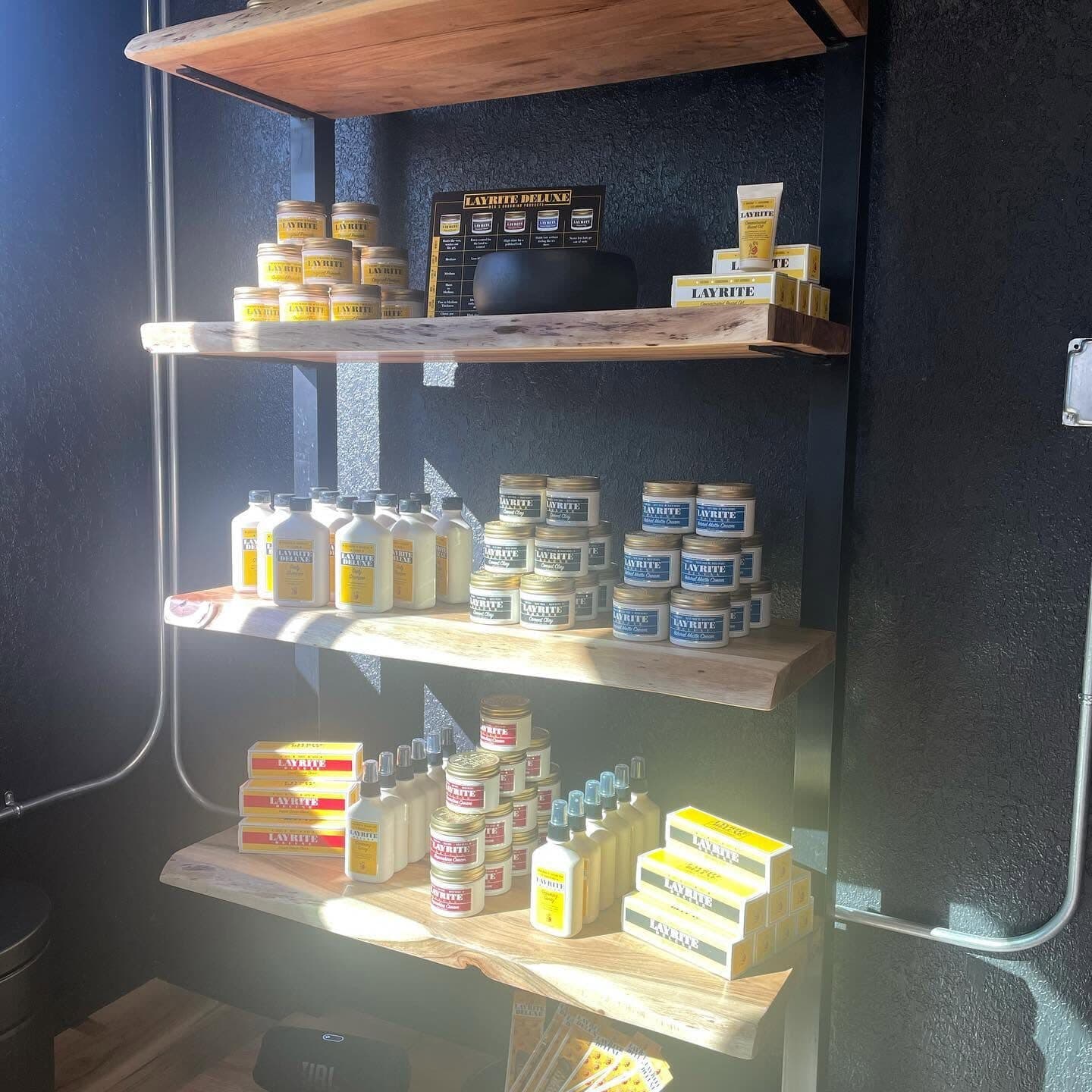 Shelves of Layrite pomade and grooming products at S|X Barbershop